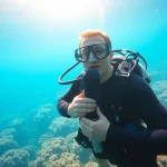 Tauchen in einer klaren Unterwasserwelt mit lebendigen Korallen und einem erfahrenen Taucher.