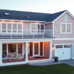 Cape Cod home featuring a modern expansion and attached garage amidst coastal beauty.
