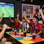 Excited fans cheering at a koora tv broadcast event with live soccer highlights.